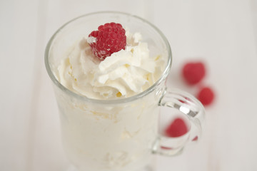 Glass with whipped cream and raspberries. Close-up
