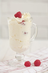 Glass with whipped cream and raspberries on a checkered napkin