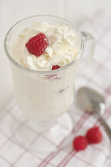 Glass with whipped cream and raspberries on a checkered napkin