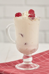 Glass with whipped cream and raspberries on a checkered napkin