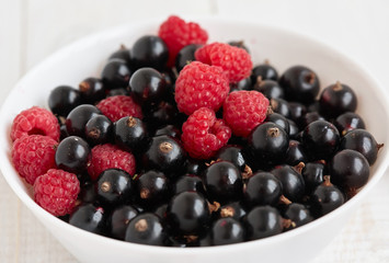 Fresh berries are in white bowl. Close up
