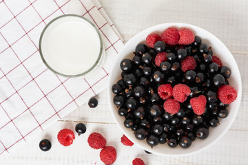 bowl with fresh berries and glass of milk