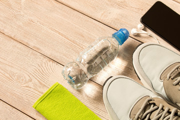 Gray running shoes and fitness accessories on wooden background. Empty text space.