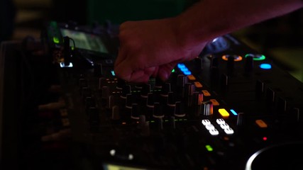 cropped shot of dj hands mixing music on mixer in flashing lights in night club