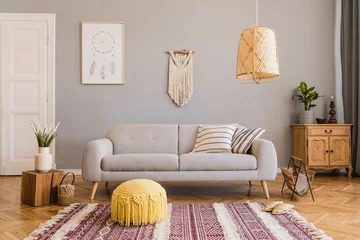 Fotobehang Boho Stylish and design home interior of living room with gray sofa, wooden cube, commode, pillow, macrame, yellow pouf, rattan lamp, basket, plants and elegant accessories. Stylish home decor. Template.   © FollowTheFlow