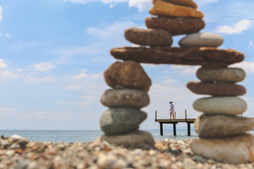 Young Woman walking on pier shown between a pebble tower on the beach at Assos, Canakkale of Aegean Sea in Turkey. (Selective Focus)