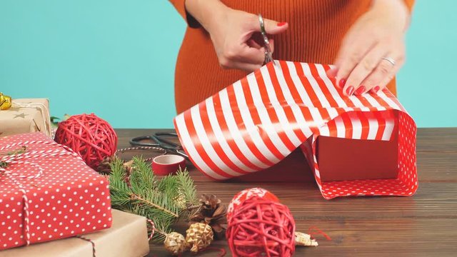 Holiday decor concept. Woman's hands tying christmas holiday handmade present in craft paper with twine ribbon. Creative hobby
