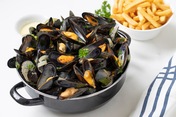 Belgian mussels with potato fries and sauce on white marble table