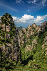Steep mountain pinnacle on the left casting a short shadow on the green valley in Huang Shan (黄山, Yellow Mountains) China