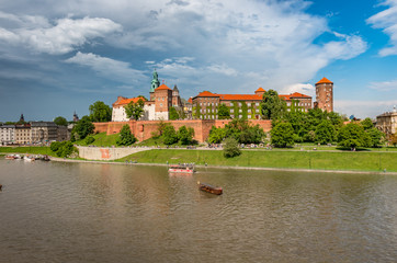 Fototapeta premium Wawel Castle and Wawel cathedral in the sun over the Vistula river on cloudy afternoon