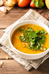 Pumpkin and fresh vegetables soup in white bowl wooden background. Natural rustic style. Vertical frame. Autumn concept.