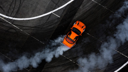 Aerial top view car drifting on asphalt race track with lots of smoke from burning tires.