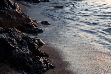 sunrise light over stones, sand and water