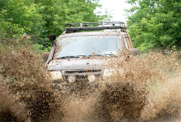off-road car driving through a puddle, a lot of spray, dirt