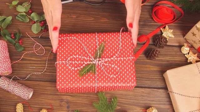 Holiday decor concept. Woman's hands tying christmas holiday handmade present in craft paper with twine ribbon. Creative hobby