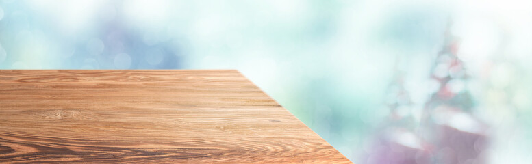 Perspective wood table with blur Christmas tree decorate string light and blue bokeh with snow light.Panoramic wooden countertop banner mock up for product display greeting card design online content