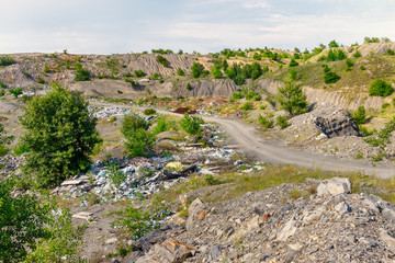 Naklejka premium The illegal garbage dump on the roadside in the old abandoned stone quarry