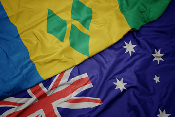 waving colorful flag of australia and national flag of saint vincent and the grenadines.