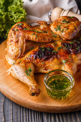 Roasted chiken on wooden board with sauce