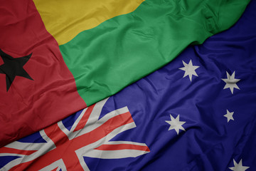 waving colorful flag of australia and national flag of guinea bissau.