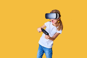 Fototapeta na wymiar Girl experiencing VR headset vs joystick game on yellow background. Surprised emotions on her face. Child using a gaming gadget for virtual reality. Futuristic goggles at young age. Virtual technology