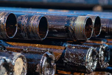 Oil Drill pipe. Rusty drill pipes were drilled in the well section. Downhole drilling rig. Laying the pipe on the deck. View of the shell of drill pipes laid in courtyard of the oil and gas warehouse