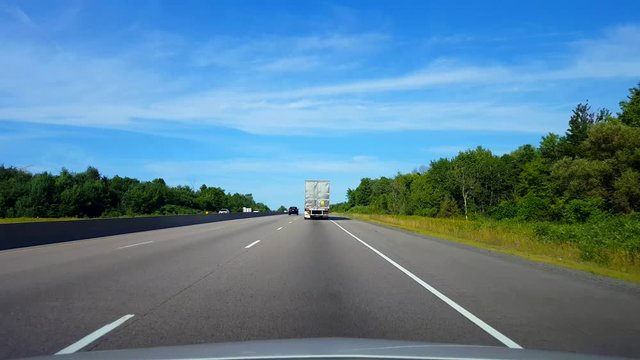 Drafting Large Truck on Highway During Summer Day.  Driver Point of View POV Slipstreaming by Following Vehicle on Interstate or Freeway or Expressway or Motorway or Turnpike.