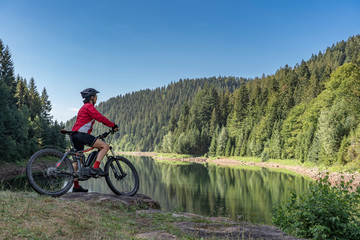 nice and ever young senior woman with her electric mountain bike at the Kinzig drinking Water...