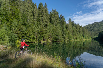 nice and ever young senior woman with her electric mountain bike at the Kinzig drinking Water...