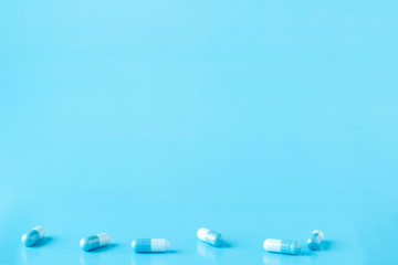 Various white-blue medication capsules. Blue background with text space