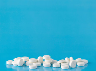 Heap of round white pills. Blue background with text space