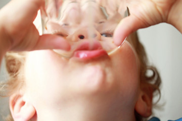 Child drinking from a glass close up portrait