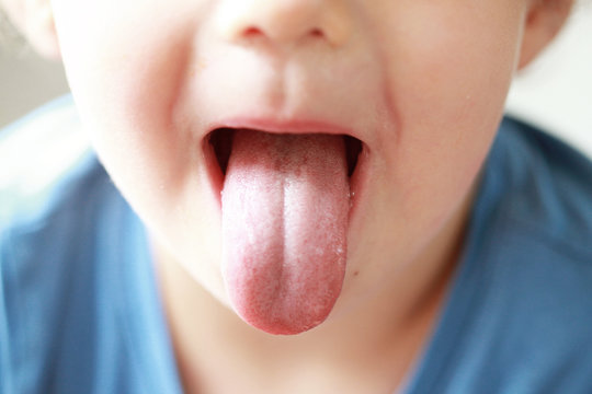 Little boy showing his tongue. Child puts out tongue - close up.