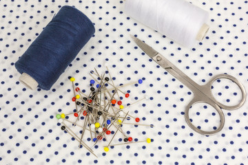 assortment of sewing accessories: thread in blue and white with bobbins, round-head needles and...