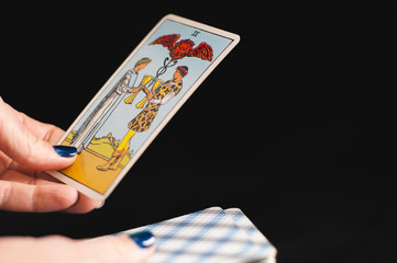 Tarot cards senior Arcana in the hands of a woman on a black background