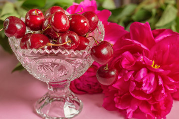 Obraz na płótnie Canvas Cherries in the beautiful crystal vase with peony