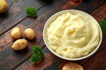 Mashed potatoes in white bowl on wooden rustic table. Healthy food