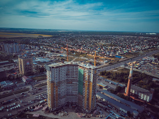 Modern building under construction with crane. Aerial view of constructing building with high crane in the evening