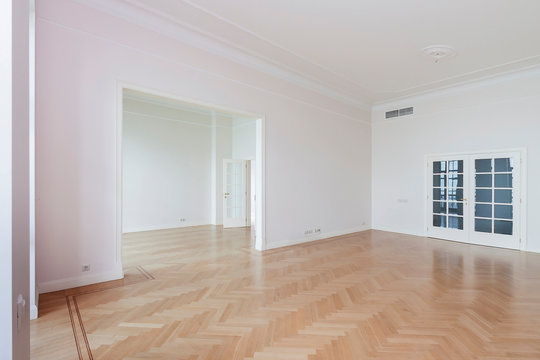 Empty room with whitewashed floating laminate flooring and newly painted white wall glass doors in background for mockup