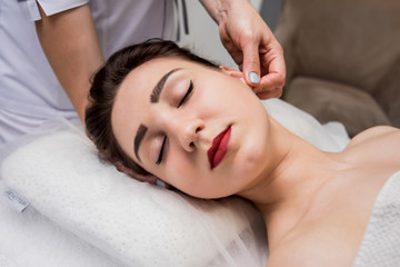 Obraz na płótnie Canvas Beautiful young woman enjoying head massage in spa salon. Cosmetology