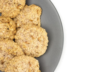 Lot of whole oat crumble biscuit on grey ceramic plate flatlay isolated on white background