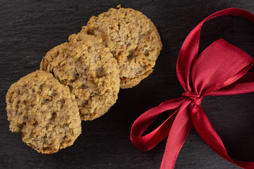 Group of three whole oat crumble biscuit with crimson ribbon flatlay on grey stone