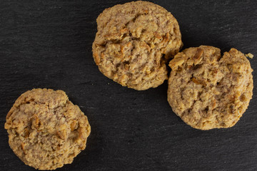 Group of three whole sweet oat crumble biscuit flatlay on grey stone