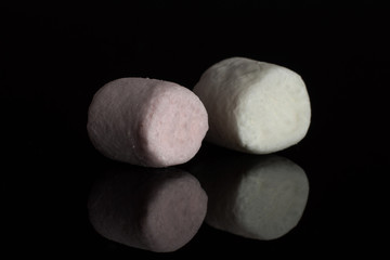 Group of two whole pastel sweet fluffy marshmallow isolated on black glass