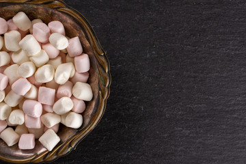 Lot of whole sweet fluffy marshmallow copyspace in old iron bowl flatlay on grey stone