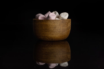 Lot of whole sweet fluffy marshmallow in wooden bowl isolated on black glass