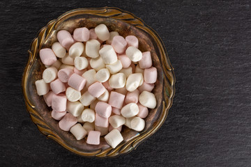 Lot of whole sweet fluffy marshmallow in old iron bowl flatlay on grey stone