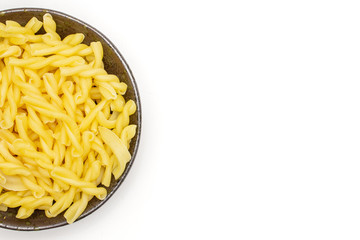 Lot of whole raw pasta gemelli copyspace on grey ceramic plate flatlay isolated on white background