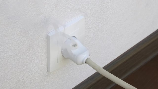smoke coming from plug in outlet from faulty wiring in apartment. Concept of beginning of fire in house.