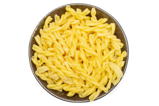 Lot of whole raw pasta gemelli on grey ceramic plate flatlay isolated on white background